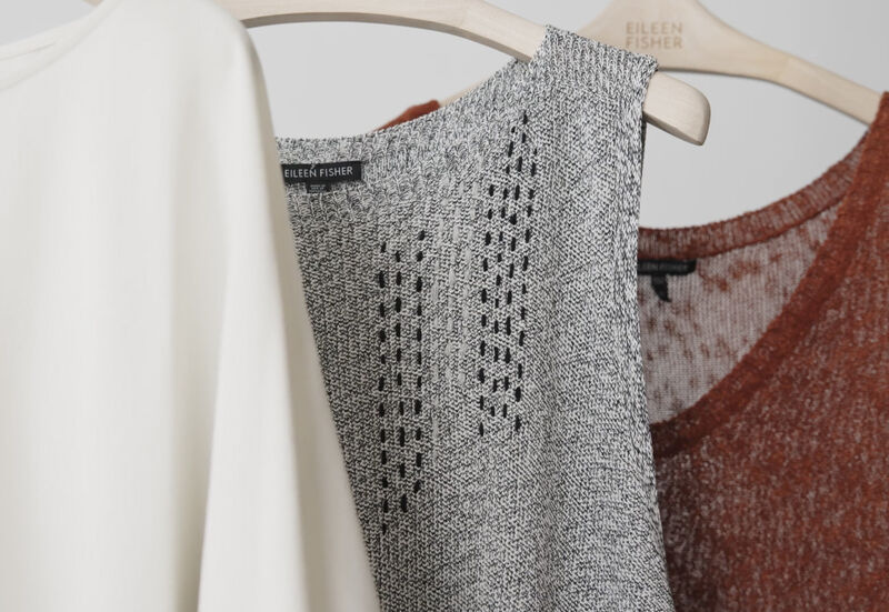 A damaged EILEEN FISHER garment that has been visibly mended with contrasting thread.