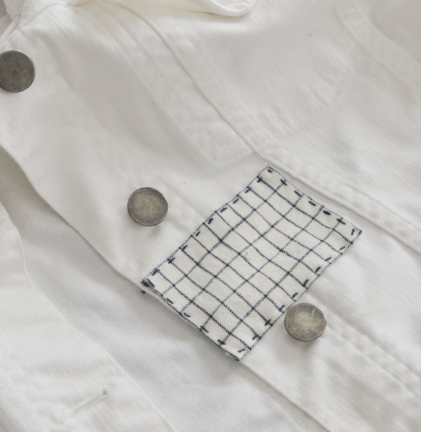 Finished blue and white rectangle patch on white denim jacket.