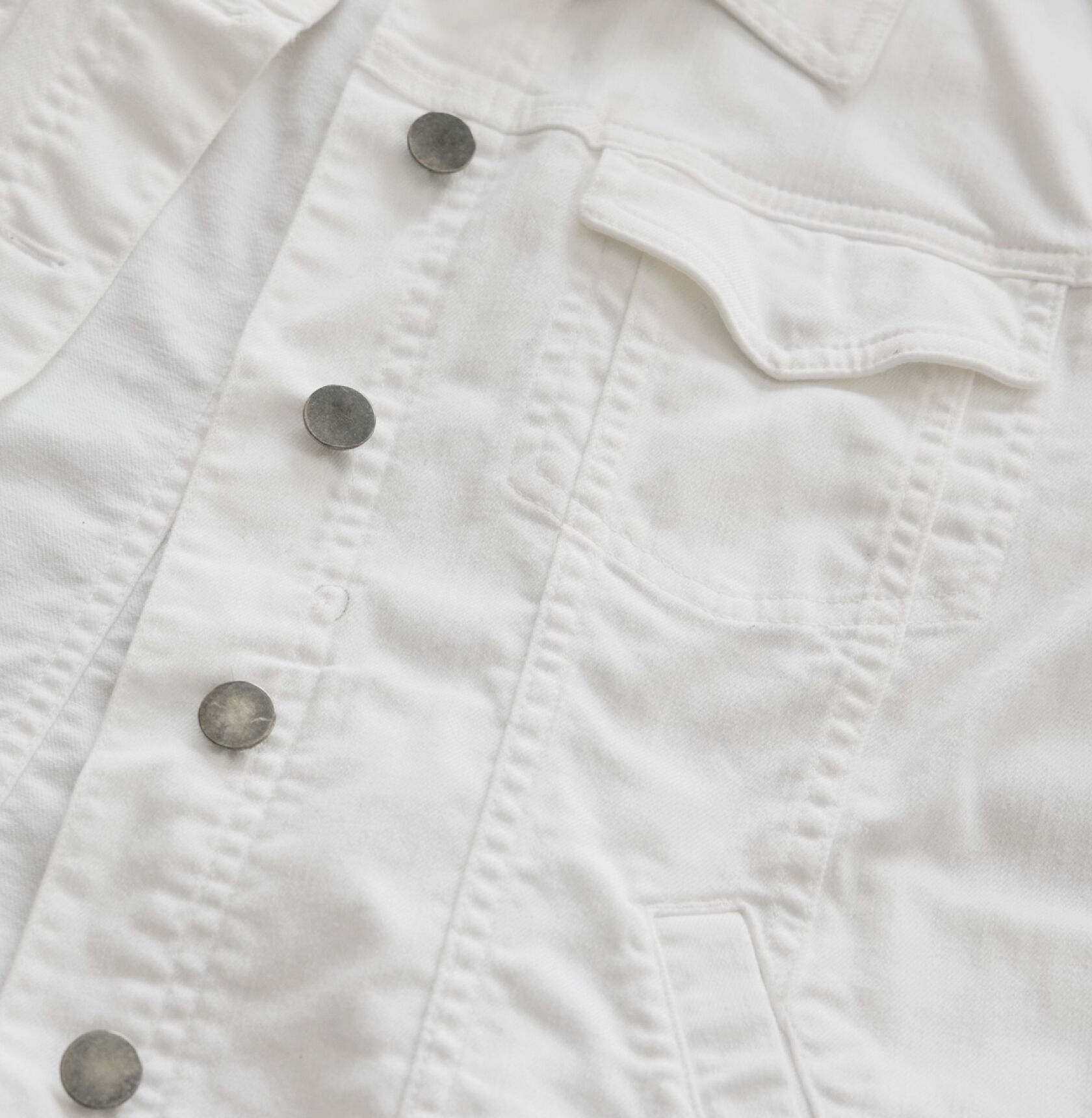 A white denim jacket with a flaw circled in pen.