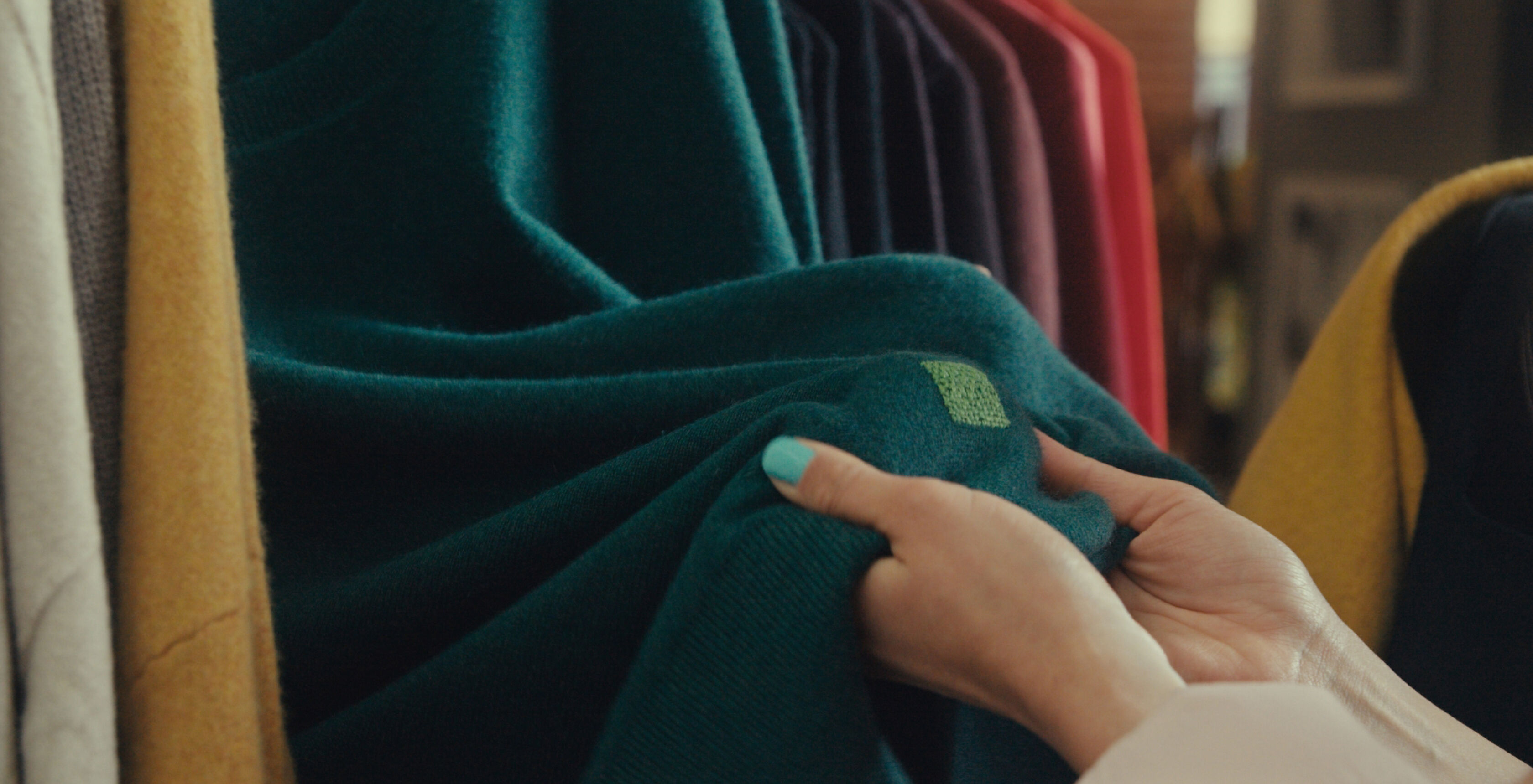 Close up of a colorful, visibly mended green sweater.