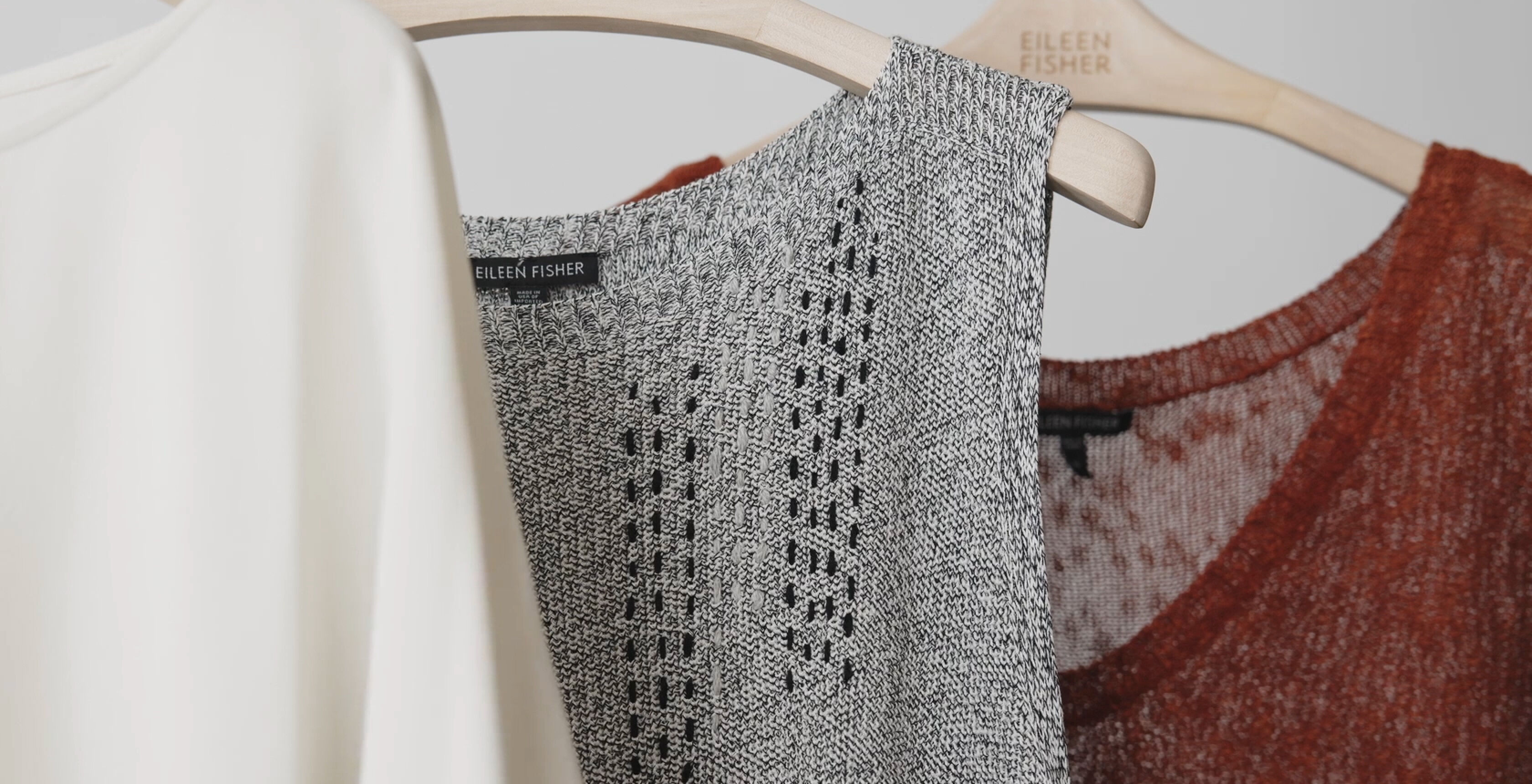 A damaged EILEEN FISHER garment that has been visibly mended with contrasting thread.