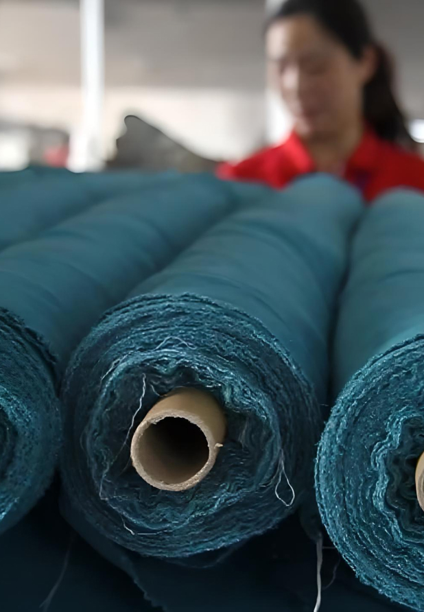 Rolls of blue fabric with woman in background.